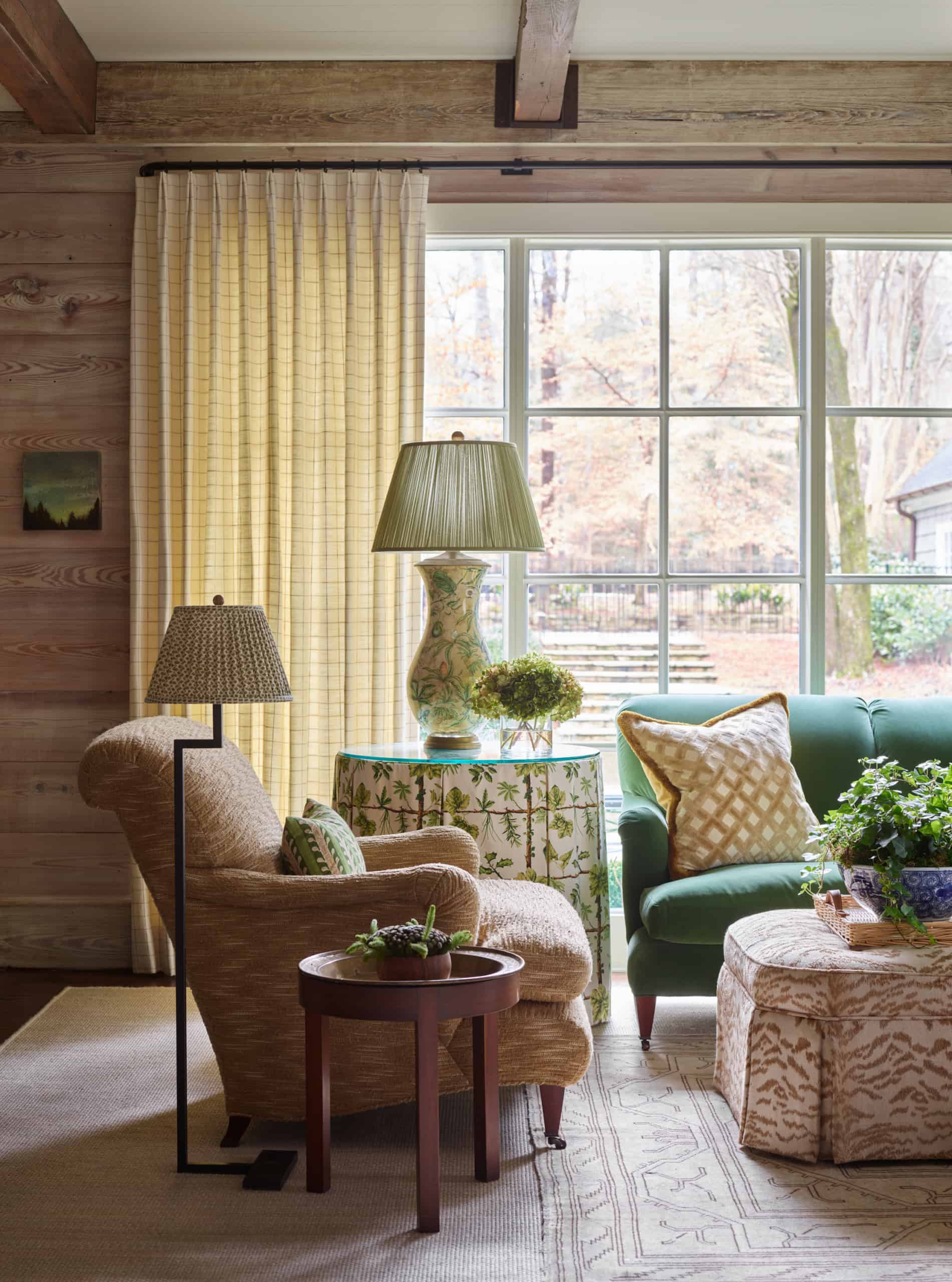 A comfortable living room with vintage furniture and large window overlooking a garden.